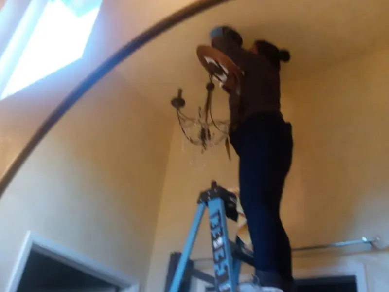 Electrician installing a chandelier in a Williamsburg residence